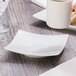 A Schonwald white porcelain saucer on a wood table with a cup of coffee on it.