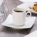 A Schonwald white porcelain saucer with a cup of coffee and a donut on it.