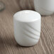 A white Schonwald porcelain salt shaker on a wood table.