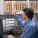 A man looking at a file cabinet in a room with a calendar on the wall.