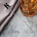 A WNA Comet clear plastic rectangular stirrer in a glass of liquid.