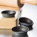 Three Matfer Bourgeat non-stick round mini cake pans on a wooden table.