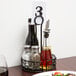 A black wrought iron condiment caddy on a table with food and wine.