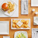 A wood table set with Acopa bright white square porcelain saucers of food.