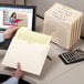 A hand opening a Smead file folder to put a piece of paper inside.