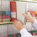 A hand holding a Smead gray/green file folder with fasteners