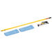 A Rubbermaid yellow mop stick with blue cleaning pads on a metal counter.