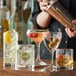 A bartender pouring a cocktail into an Acopa Coupe Cocktail Glass.