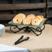 A rectangular black metal display frame with a plate of bagels on a table.