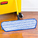 A Rubbermaid blue and white microfiber mop pad on a wood floor.