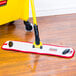 A red Rubbermaid HYGEN microfiber wet mop pad on a wood floor.