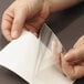 A hand holding a piece of paper with a Smead clear self-adhesive poly pocket.