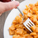 A Libbey stainless steel dinner fork spearing a piece of pasta with cheese.