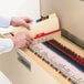 A person's hands opening a file drawer filled with Smead legal size folders.