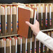 A hand picking up a Smead letter size file from a shelf.