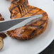 A Libbey fluted hollow handle dinner knife and fork on a plate of meat.