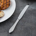 A plate of food with a Libbey Antique stainless steel dinner knife next to a steak.