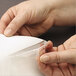 A person's hands holding a clear plastic strip with paper inside.