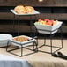 A table with a Libbey Versa Riser holding bowls of fruit.