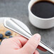 A person holding a Libbey Cortland stainless steel serving spoon over a bowl of cereal and a cup of coffee.