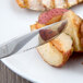 A World Tableware Columbus stainless steel knife cutting food on a white plate.