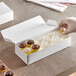 A person holding a white 1-piece candy box filled with chocolates.