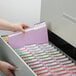 A hand holding a purple Smead file folder opening a file cabinet.