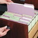 A person opening a file drawer with several Smead lavender file folders inside.