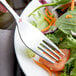 A Libbey stainless steel salad fork on a plate of salad.