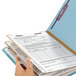 A hand holding a blue Smead SafeSHIELD letter size classification folder.