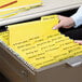 A person holding a Smead yellow FasTab file folder.