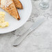 A Libbey stainless steel bread and butter knife on a plate of toast with butter.