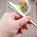 A hand holding a Libbey stainless steel iced tea spoon over a cup of tea.