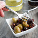 A Libbey stainless steel cocktail fork with olives in a bowl.