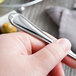 A person holding a Libbey stainless steel cocktail fork.