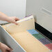 A hand opening a file drawer with a Smead manila file folder inside.