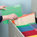 A hand holding a red Smead file folder.