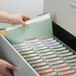 A hand putting a Smead file folder into a file drawer.