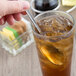 A hand holding a Libbey Cortland iced tea spoon in a glass of iced tea.