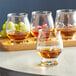 A table with glasses of bourbon and fruit on it, including a Reserve by Libbey Kentucky Bourbon Trail Tasting Glass filled with bourbon and grapes.