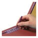 A person's hand using a purple pen to write on a red Smead classification folder.