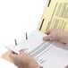 A person holding a Smead Shelf-Master letter size fastener folder with a piece of paper.