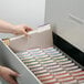 A person putting a Smead file folder into a file drawer.