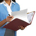 A woman holding a Smead classification folder and writing on a piece of paper.