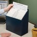 A hand putting papers into a navy Smead stadium file folder.