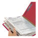 A hand holding a red Smead SafeSHIELD classification folder with documents inside.