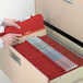 A hand holding a red Smead SafeSHIELD classification folder.
