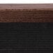 The walnut wood surface of an Aarco enclosed message board with black trim.