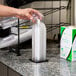 A person using a Vollrath countertop dome lid holder to dispense a plastic lid.