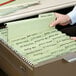 A hand putting a Smead FasTab file into a file drawer.